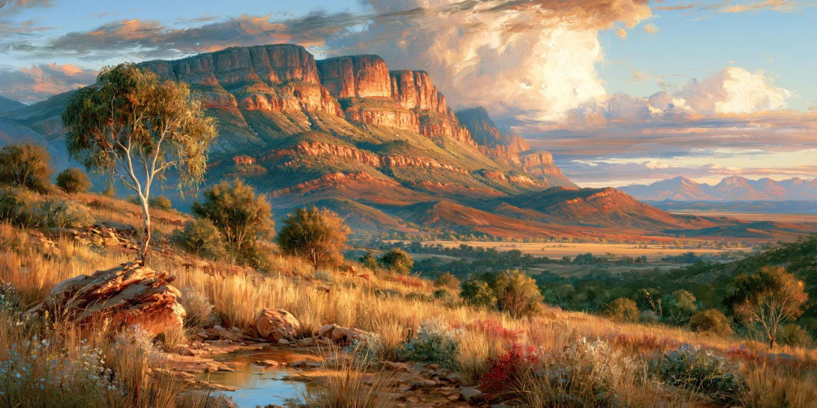 A small blue pool lies among foreground rocks and golden grasses below a pale tree at left, with a broad orange escarpment and large cream clouds beyond.