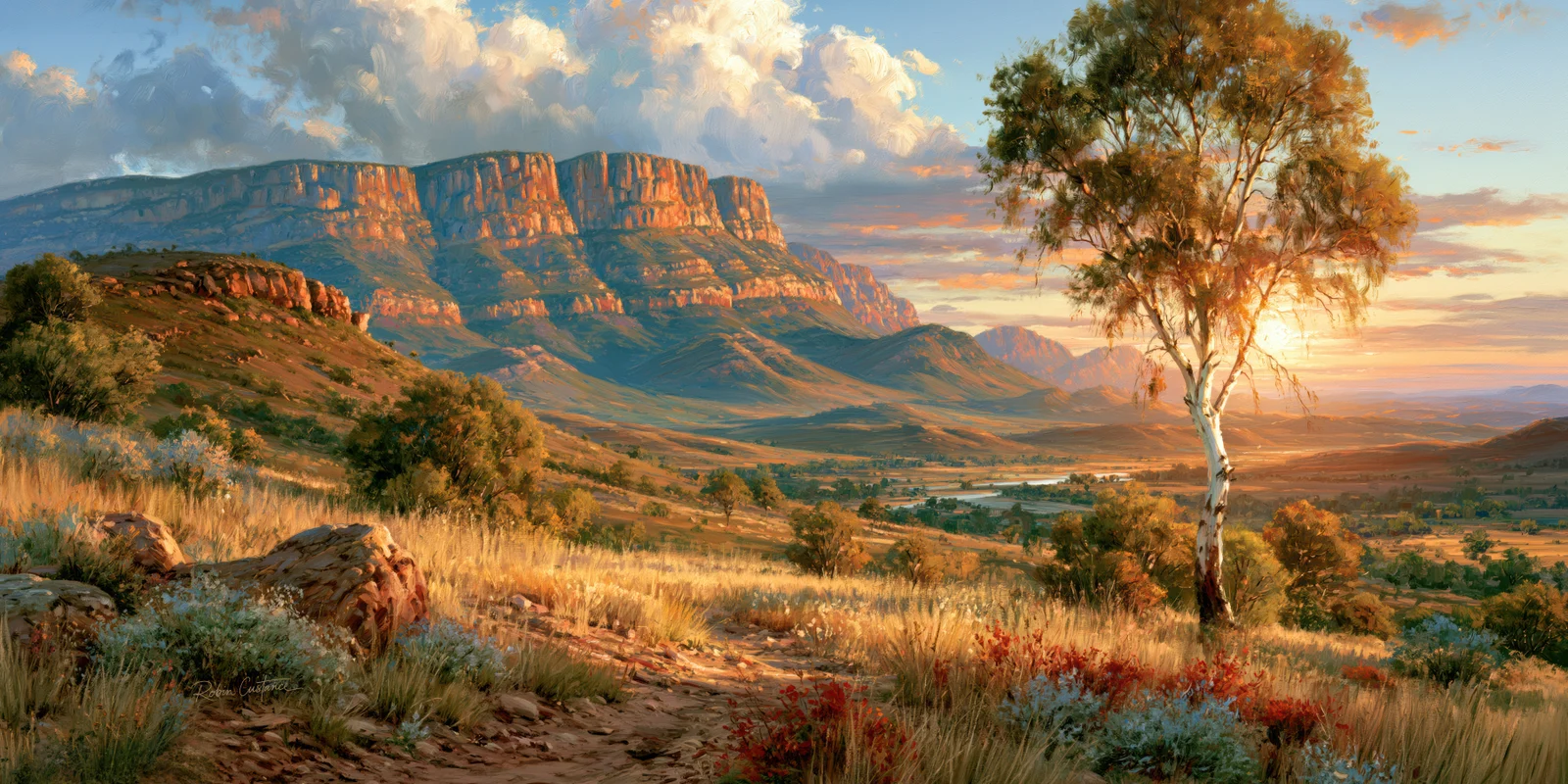 A pale-trunked tree on the right is backlit by a low sun beside orange cliffs, blue-green hills, a distant valley and a rocky foreground with golden grasses.