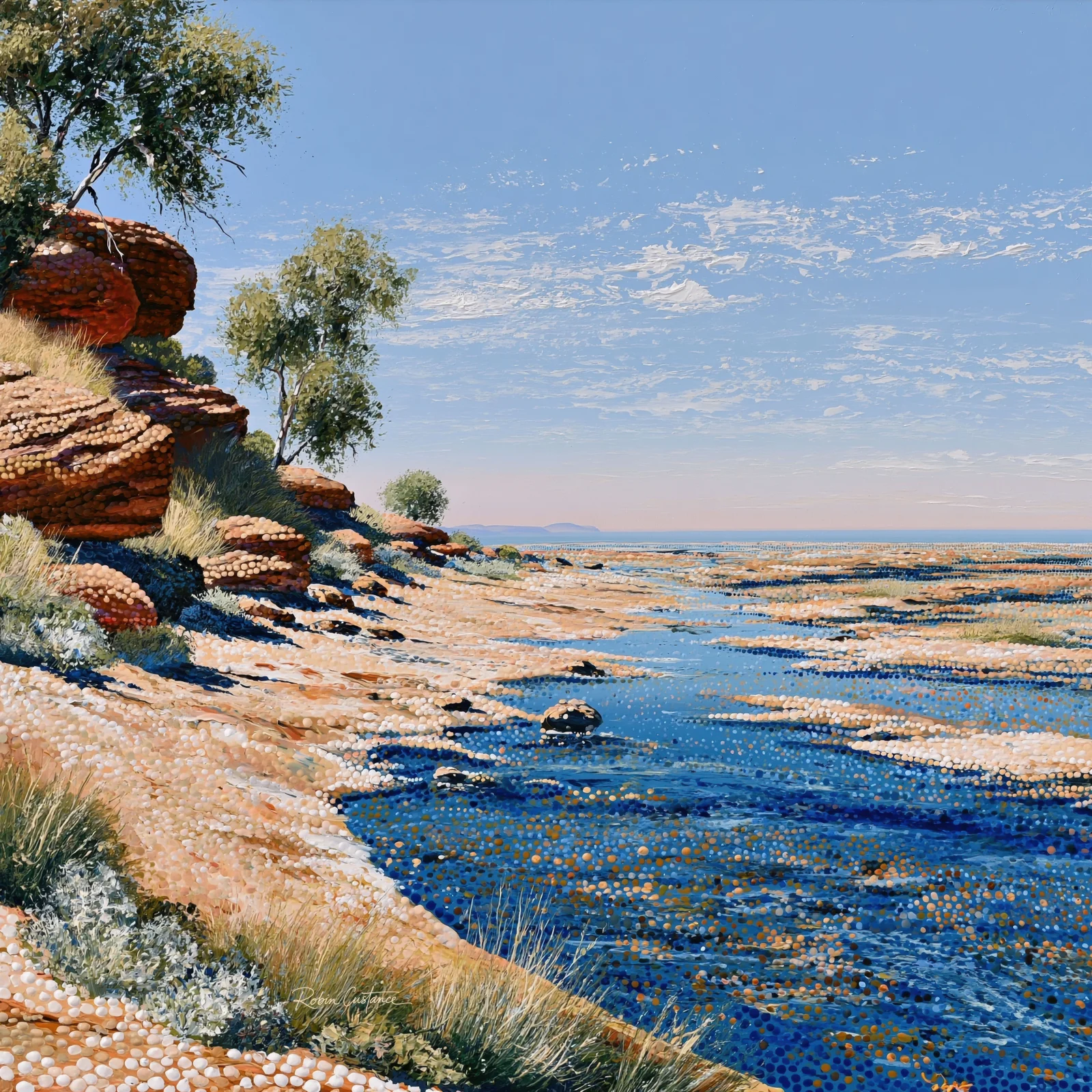 Blue rock pools spread between pale rocky shelves below a wide blue sky, with rust-coloured boulders, grasses and trees along the left edge.