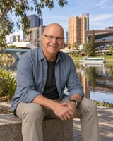 Robin Custance seated beside the river with an Adelaide backdrop